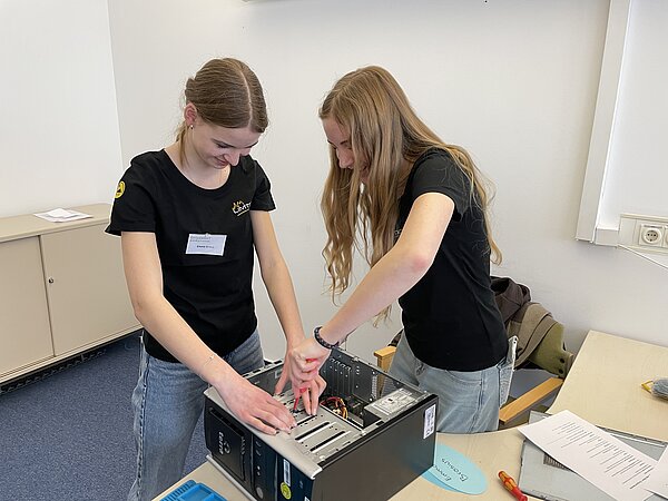 Zwei Frauen bauen einen Computer zusammen.